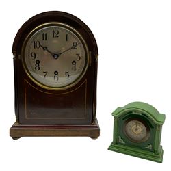 An early 20th century arch topped mahogany mantle clock with inlaid satinwood stringing on a moulded plinth with four turned feet, two shaped side pillars with brass capitals and reed moulding,  6” slivered metal dial with upright Arabic numerals and minute track, pierced steel hands within a spun brass bezel and convex glass, with an English eight-day spring driven movement striking and chiming the hours and quarters on five coiled gongs, with an engraved presentation plaque dated 1925.
With key and pendulum.
H36 W24 D18

With a porcelain German bedside clock with an ivorine dial and stamped gilt dial center, steel spade hands, brass bezel with beveled flat glass, timepiece movement with integral key. 
H13 W13 D6
