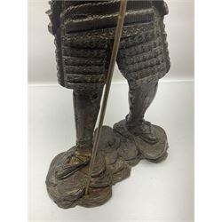 Bronze figure of a samurai standing wearing armour and holding a naginata, upon a rocky base, H48cm