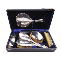 Early 20th century silver mounted five piece dressing table set, comprising hand held mirror, two hair brushes, and two clothes brushes, each engraved with monogram, hallmarked William Devenport, Birmingham 1919, contained within a fitted case, together with two further early 20th century silver mounted clothes brushes, also bearing engraved monograms, hallmarked Levi & Salaman, Birmingham 1919