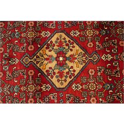 Large Persian Qashqai runner rug, the red ground decorated with navy and ivory lozenge medallions interspersed with stylised floral and geometric motifs, enclosed by an ivory flowerhead border and patterned guard stripes