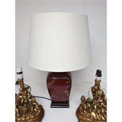 Ceramic table lamp, decorated with gold leaves on a red ground, together with a pair of figural table lamps, modelled as a group of putti, in a gilt finish on wooden base, tallest H62cm