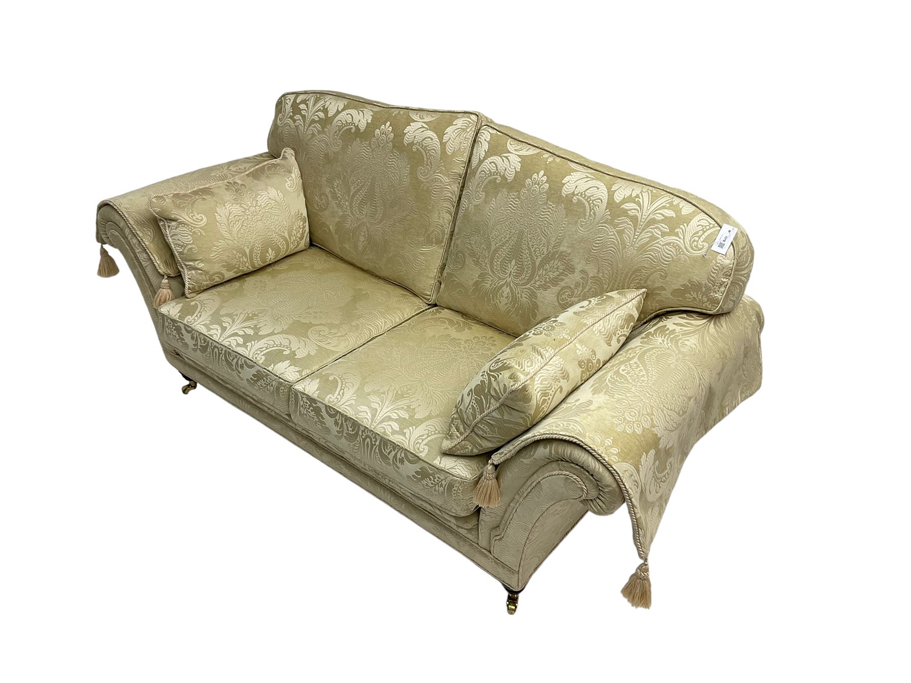 Steed Upholstery - two seat traditional shaped sofa, upholstered in cream fabric with scrolling foliate pattern, on turned front feet with brass castors, with side cushions and arm covers