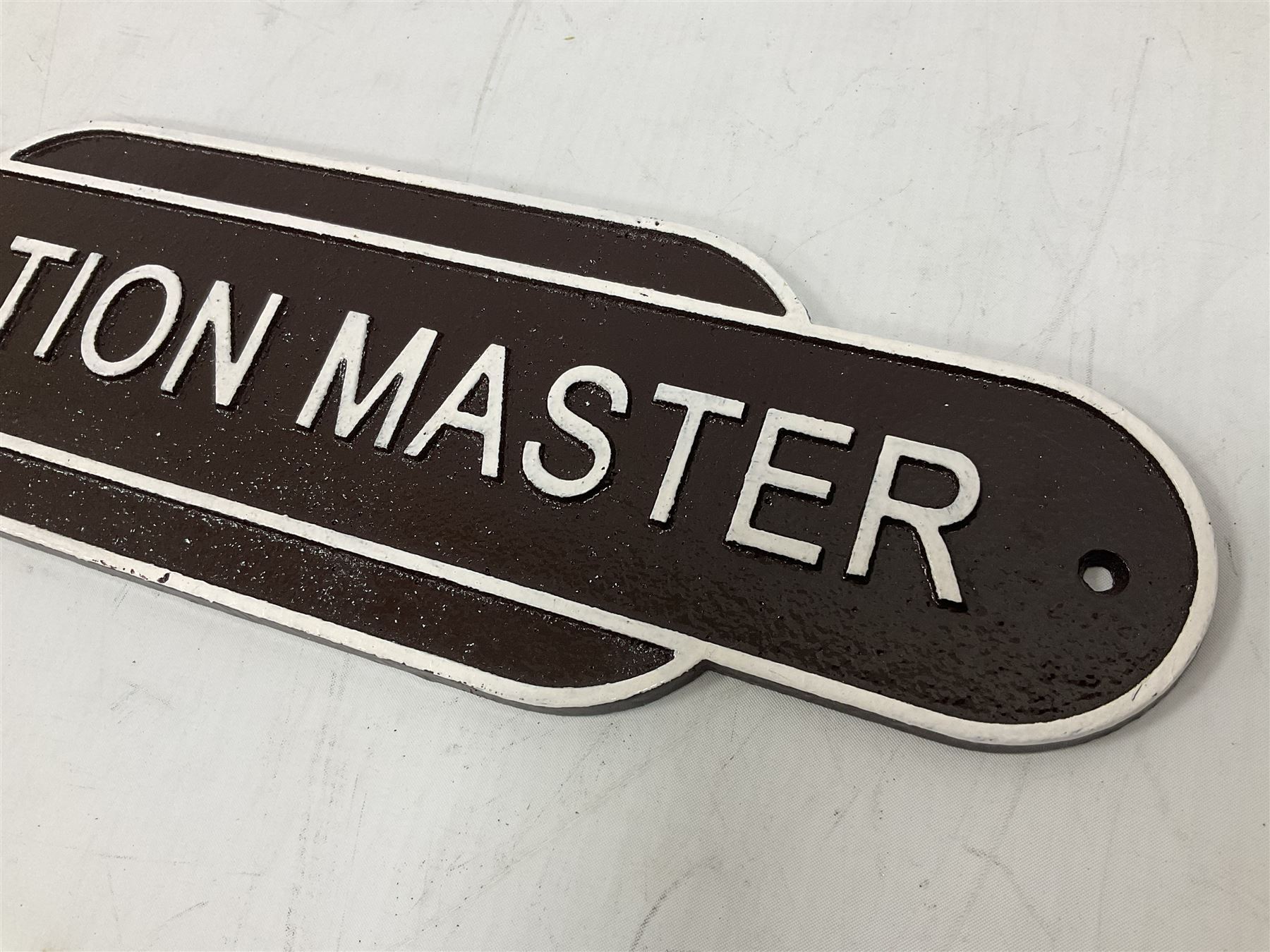 Cast iron Station Master wall plaque on a brown ground, L39cm