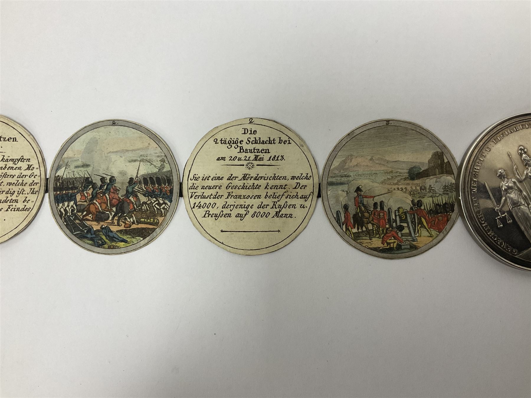 Grolier Club’s silver Schraubmedaille to commemorate the German campaign of 1813, obverse depicts a Greek temple, below “Eintracht Überwindet Alles”, the reverse depicts three figures and the text “Gerechtigkeit. Weisheit. U. Einigkeit. Beglücken. D.: Menschheit”, inside are twelve circular hand coloured engravings depicting six major battles of the German campaign, each with corresponding descriptions, D
