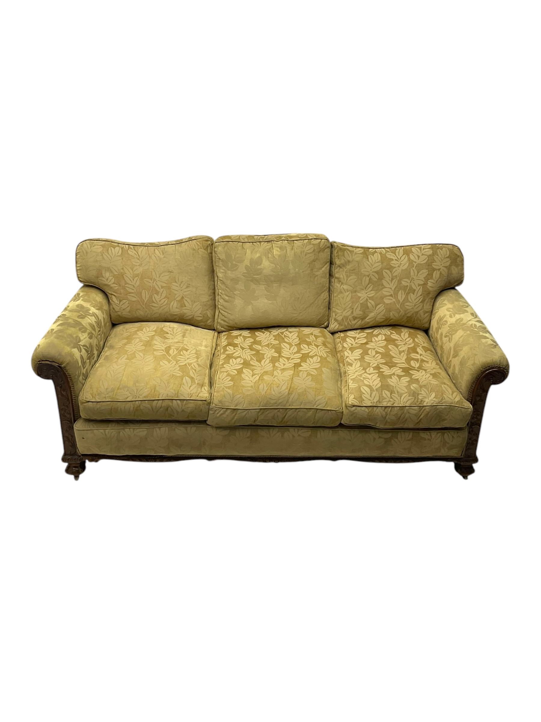 Early 20th century mahogany framed three-piece lounge suite - three-seat camelback sofa (W203cm, D105cm); pair of matching armchairs (W95cm, D96cm); upholstered in neutral foliate pattern fabric, carved with trailing leafy branches, ball and claw carved feet with brass castors 