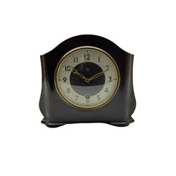 A Retro Art-Deco 1950's Bakelite cased mantel clock with a Smiths timepiece movement housed in a domed top case with curved sides on raised feet, dial with a cream chapter ring, upright Arabic numerals and minute markers, inscribed “Smiths, Made in Great Britain”, dial enclosed within a spun brass bezel and a convex glass, gilt pierced hands, spring driven 8-day pendulum movement. 
With pendulum.
