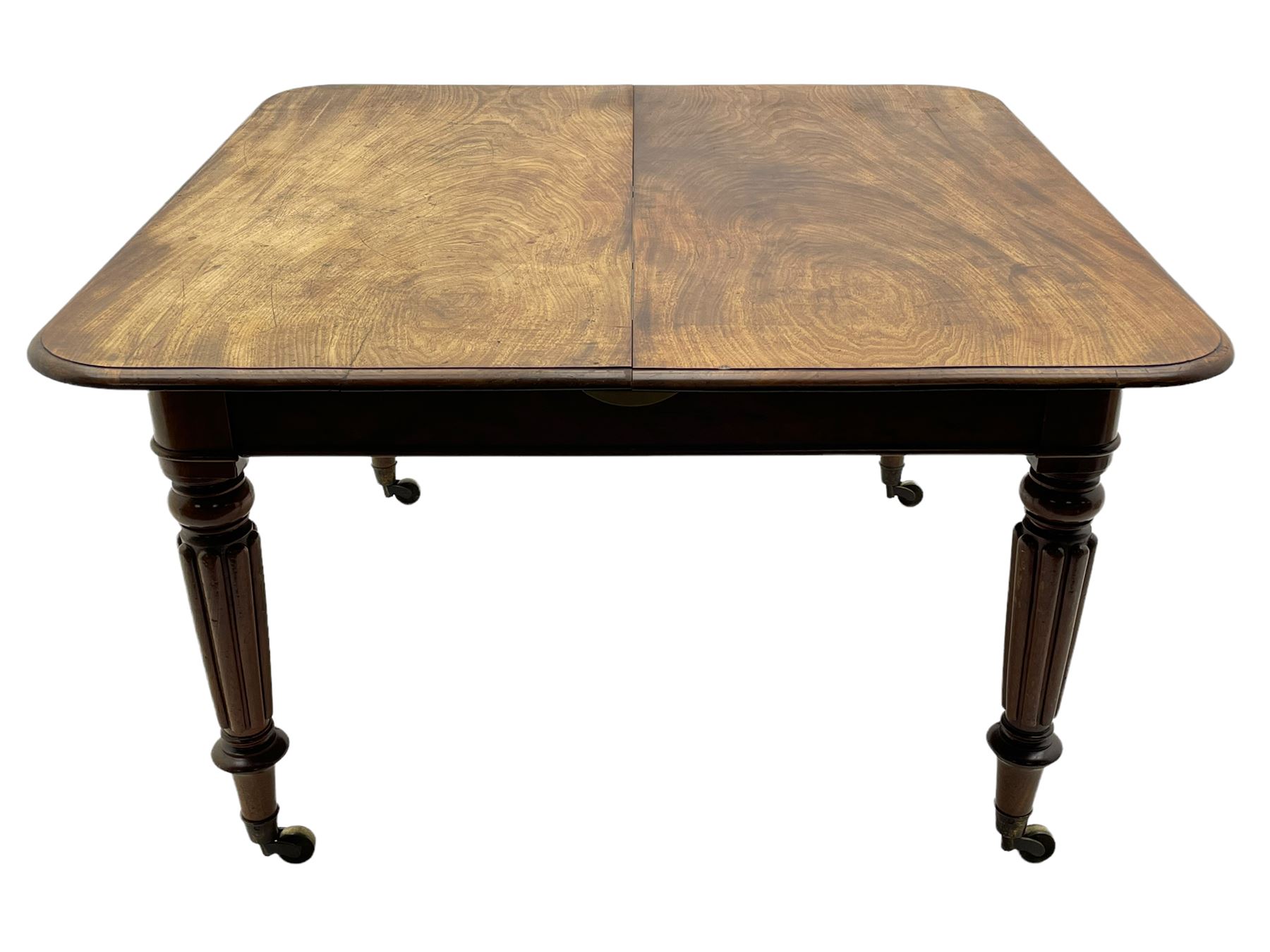 Early 19th century figured mahogany extending dining table, the rectangular top with moulded edge and rounded corners, pull-out action with three additional leaves, raised on turned and lobe carved supports with brass cup castors