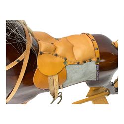 Contemporary carved wooden rocking horse, with leather saddle and bridle, horsehair mane and tail, raised on a pine stand with swing iron supports