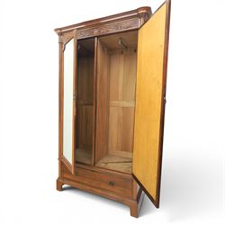 Edwardian walnut double wardrobe, featuring two mirrored doors with bevelled plates, carved frieze with fluted pilasters, above single base drawer
