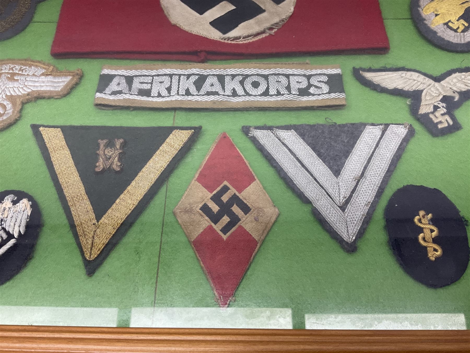 Framed display of thirty-four WWII German cloth badges including Luftwaffe pilot, Paratrooper, Afrikakorps cuff title, sleeve insignia for 'SS' Foreign Volunteers, various breast eagles including Luftwaffe, Army etc, RAD badges, Party Armband, rank and trade insignia, cap insignia etc; 40 x 50cm in modern pine frame