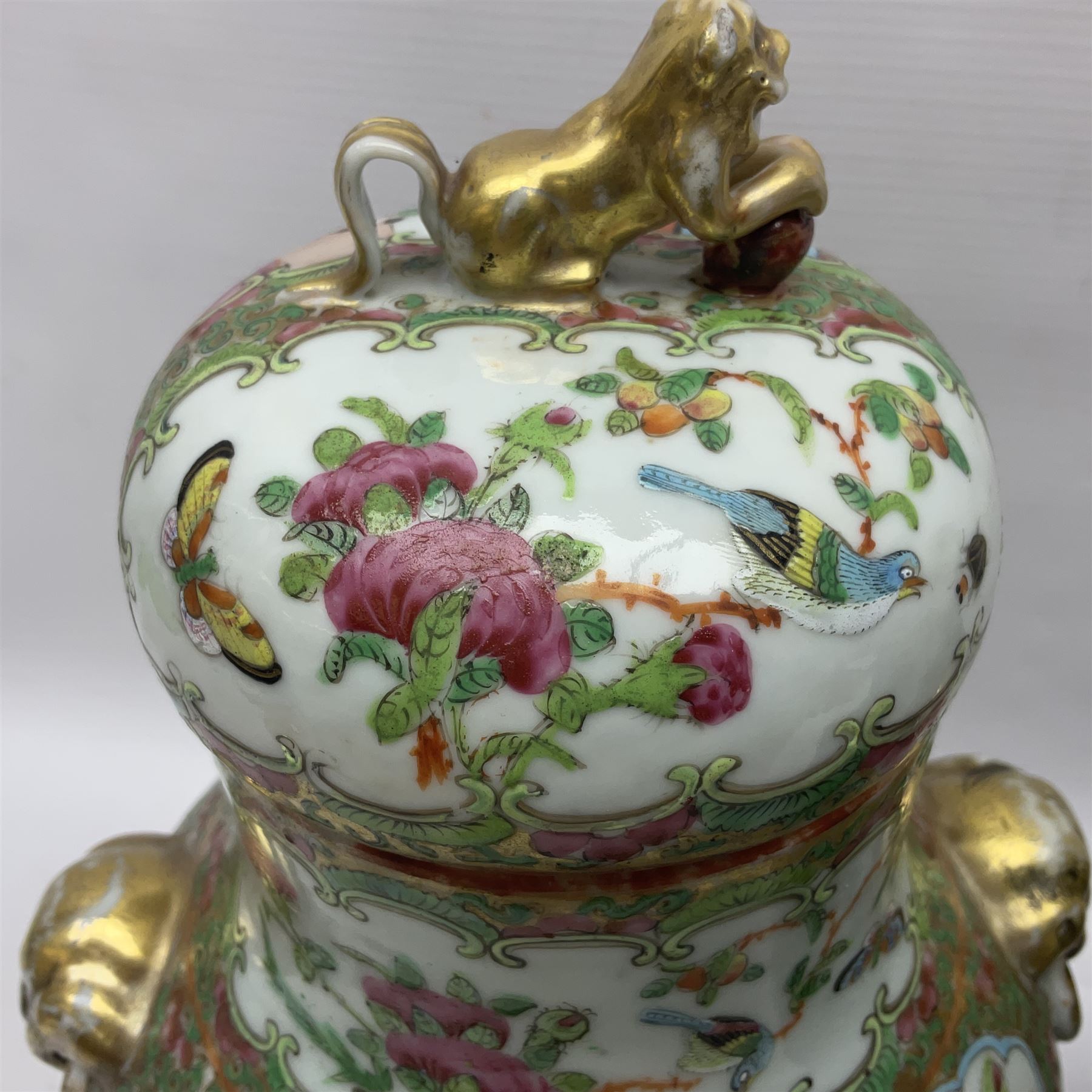 Pair of 19th century Chinese Famille Rose vases and covers, each of baluster form with twin gilt lion mask ring handles to shoulders, the flattened domed covers with gilt temple lion finials, each decorated with alternating reserves of bijin and attendants, and birds and butterflies amongst blossoming peonies, against a gilt ground profusely decorated with stylised scrolls, H32.5cm