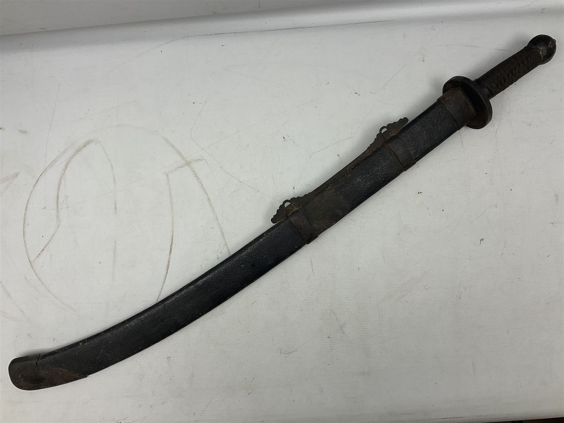 Chinese Boxer Rebellion Period Sword, 69.5cm heavy curved single edge blade with single narrow fuller, plain iron dished circular guard, iron pommel and ferrule with plaited cord bound grip; in skin covered wooden scabbard with iron chape and long suspension mount L95cm overall