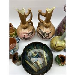 Collection of Devon pottery all having floral slip decoration and include Aller Vale, Watcombe, possibly some Longpark, and other unmarked pieces, tallest H25cm together with a pair of T. Forester jugs hand-painted with cranes and two further Devon pottery pieces, both hand-plated with birds 