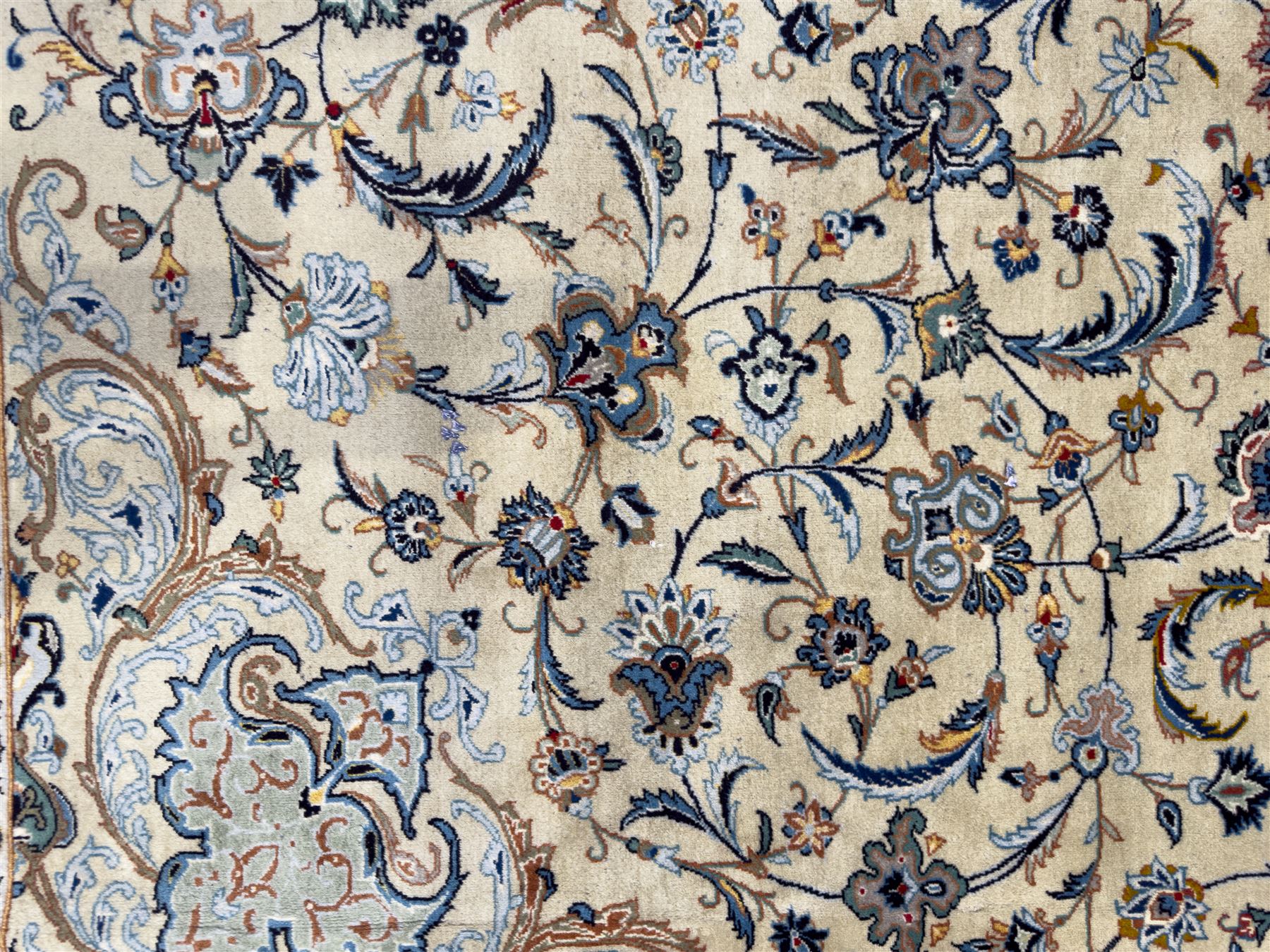 Central Persian Kashan hand-knotted carpet, ivory field with scrolling vines, palmettes, and rosettes around a cusped medallion with pendants and spandrels within a blue ground border of palmettes and flowerheads, 388cm x 300cm