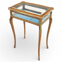 Early 20th century French mahogany bijouterie table, the hinged shaped rectangular top with brass edge and gilt-metal foliate slip enclosing bevelled glass plate, raised on cabriole supports with applied gilt-metal cartouche and foliate mounts