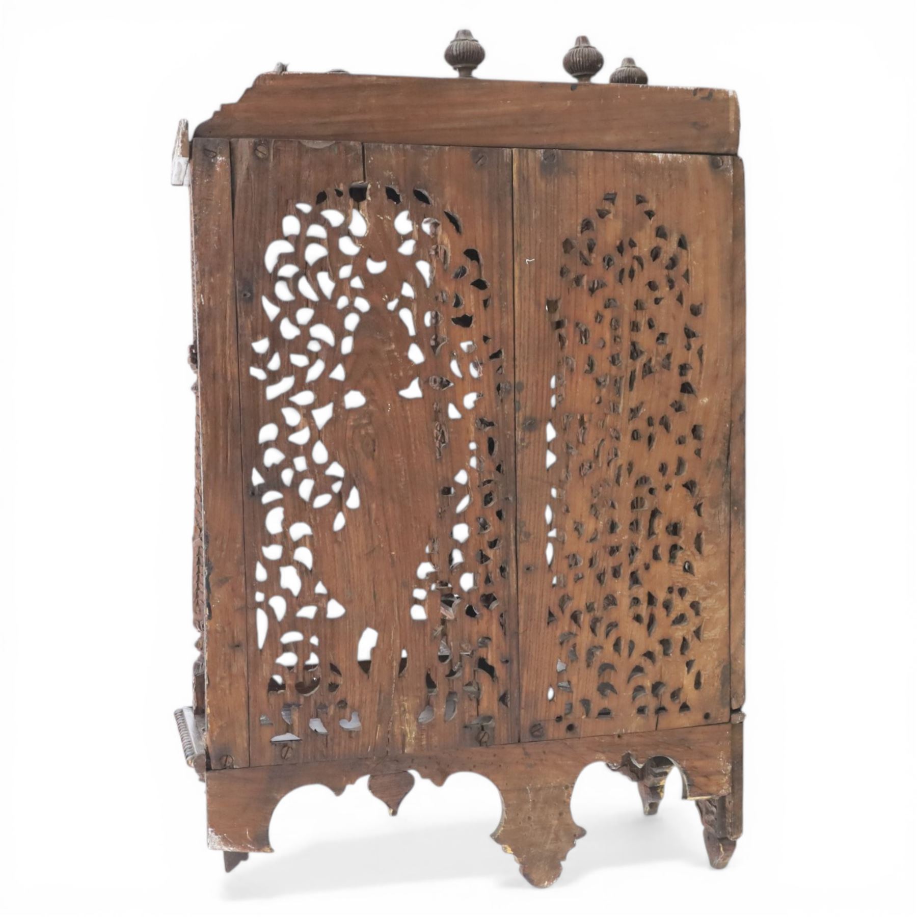 20th century Indian carved hardwood corner shelf, the tiered pagoda form with pierced and carved foliate panels centred by figural carving, supported by turned and carved columns, with shaped brackets and pendant finials