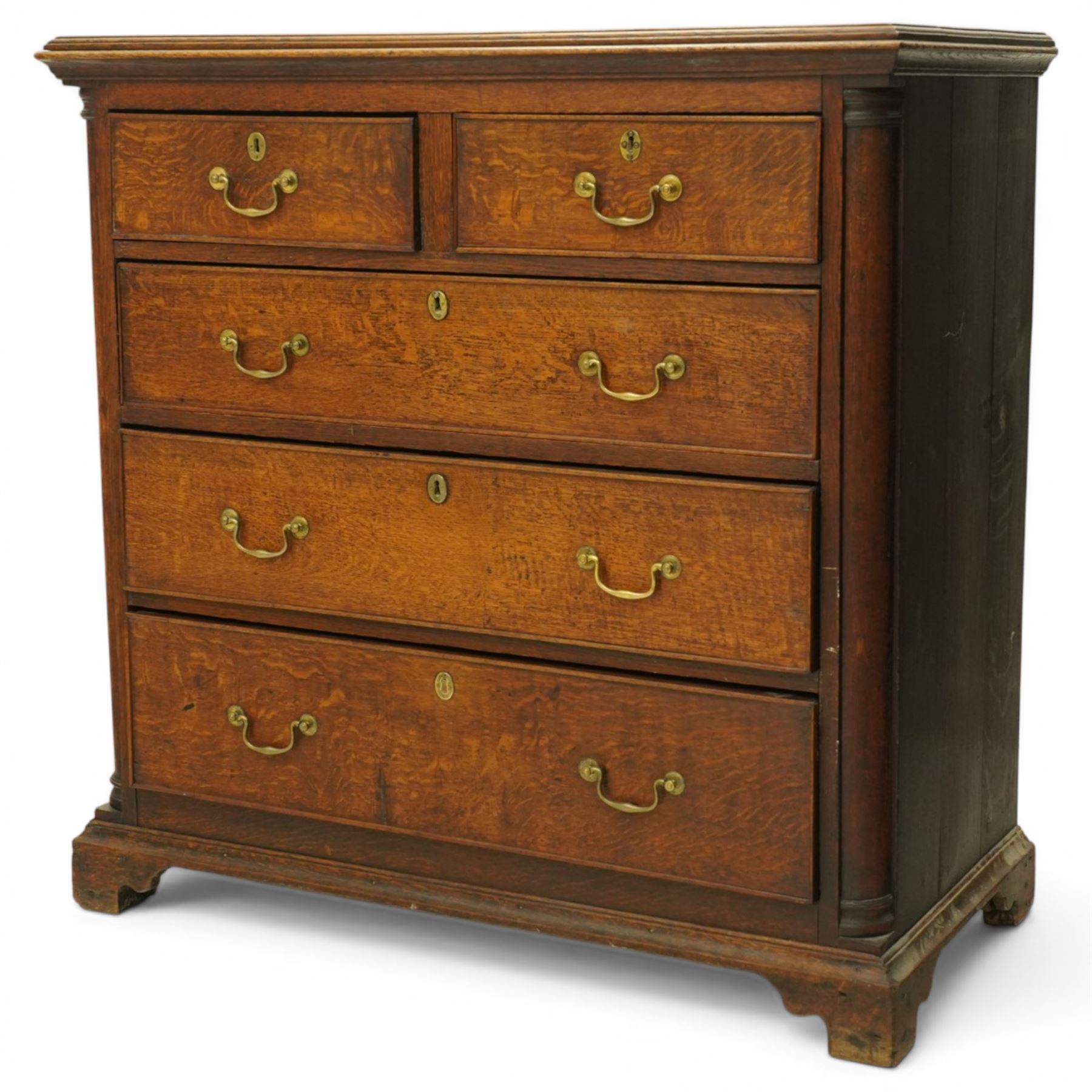 Georgian oak chest of drawers, fitted with two short over three long drawers, with brass swing handles and escutcheons, flanked by quarter turned pilasters, raised on shaped bracket feet