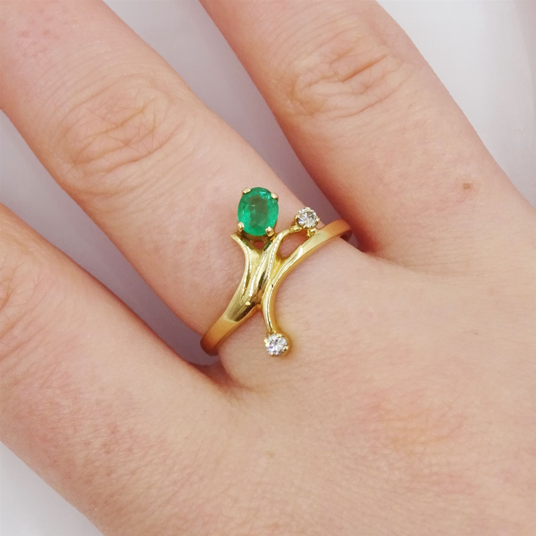 Gold three stone oval cut emerald and round brilliant cut diamond ring
