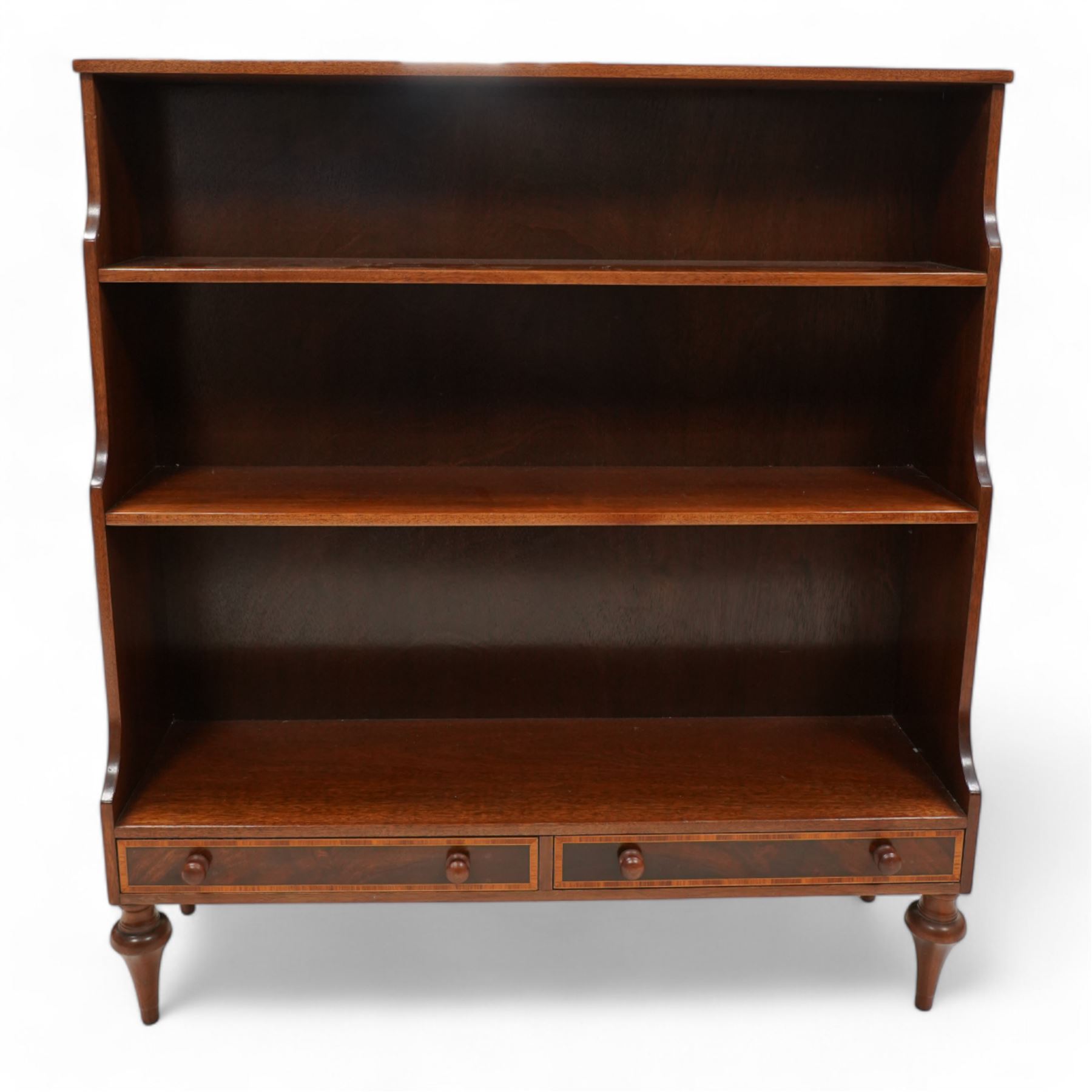 Mahogany waterfall bookcase, fitted with two fixed shelves over two drawers, the drawers with satinwood bands and turned handles, on turned tapering feet 