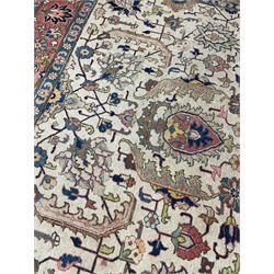 Persian carpet, pale ground with floral medallion, the field decorated with stylised plant motifs, geometric interlacing, the guarded border with repeating flower head design