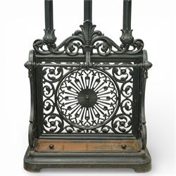 Late 19th century cast iron stick stand, the arched back with scrolling foliate decoration, fitted with multiple hooks, the lower section with pierced panels centred by a radiating sunburst motif, raised on a rectangular drip tray base