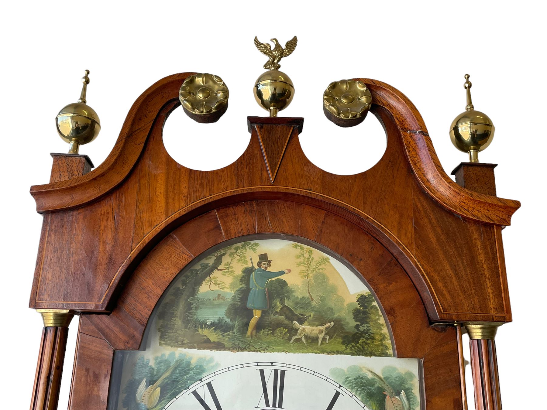 An oak and mahogany longcase clock by William Hewson, Lincoln c 1860, with a swans neck pediment, ball and spire finials and brass paterae, break arch hood door flanked by reeded pilasters with brass capitals, oak trunk with canted corners and a short oak door with mahogany crossbanding, conforming plinth with applied skirting, fully painted dial with Roman numerals, minute track and subsidiary seconds dial, matching brass stamped hands and winding collets, depiction of a  sportsman to the break arch and corresponding game birds to the spandrels, dial pinned directly to an eight-day rack striking movement with a recoil anchor escapement, striking the hours on a bell. Original casemakers label pasted to the inside of the case 