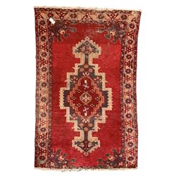 Persian red ground rug, the field decorated with geometric pole medallion, floral decorated spandrels and repeating border 