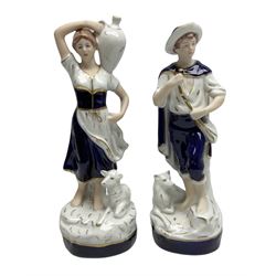 Pair of Royal Dux figures to include Shepherdess carrying a water jug with a recumbent lamb beside her, together with a male carrying a bag with a hound at his feet, both with applied pink triangle marks beneath, no. 2262 and 2261, H24cm
