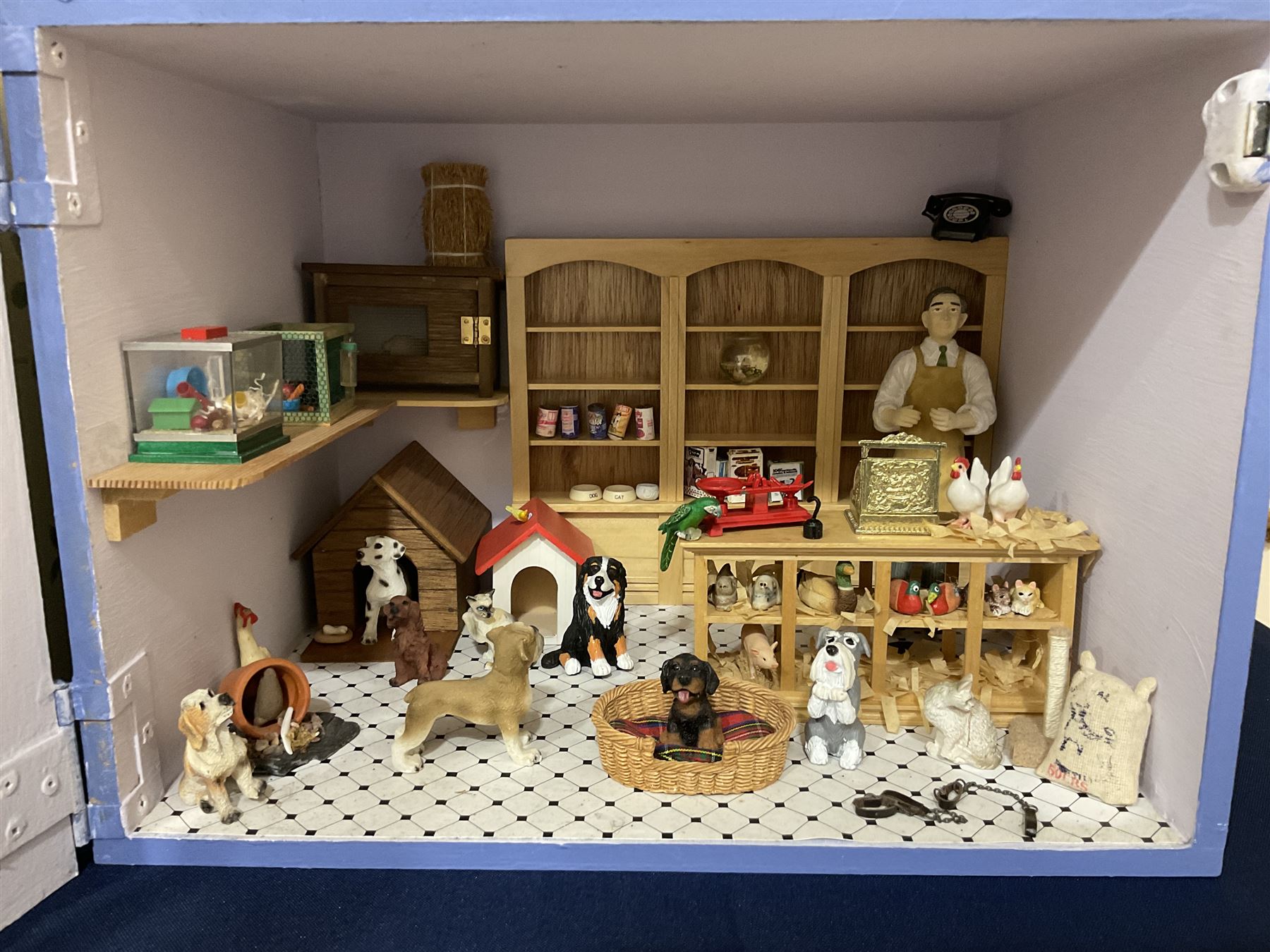 Three scratch-built wooden shop dioramas - single room Pet Shop with hinged front, fully furnished and well stocked with animals, birds and numerous accessories; and matching Garden Shop, fully furnished and well stocked with fruit, vegetables and garden accessories including lawn mower, wheelbarrows etc; each W34cm H27cm D26cm; and double fronted single room Butchers Shop with butcher at his block, partially stocked counter and two delivery cycles W57cm (3)