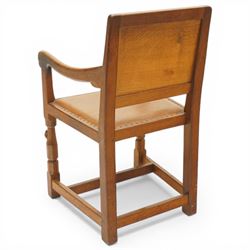 Mouseman - oak panel back carver armchair, lightly adzed panel back above a tan seat with brass studded trim, flanked by swept arms raised on octagonal front supports, with carved mouse signature, by the workshop of Robert Thompson of Kilburn