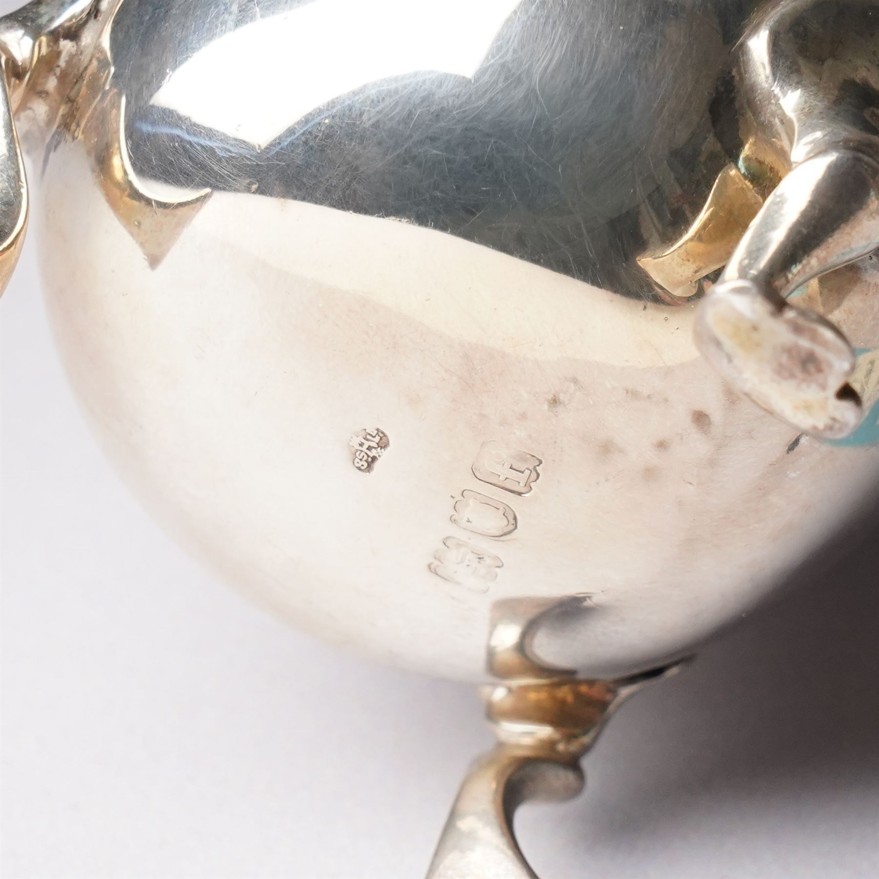 Silver square tea caddy with hinged lid and canted corners H9cm Birmingham 1912 Maker Synyer & Beddoes and a silver cream jug with crimped rim and scroll handle engraved with a crest  London 1901 Maker William Hutton & Sons
