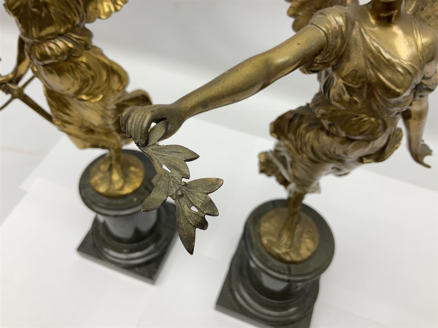 After Oswald Schimmelpfennig (German, 1872-1939): Pair of gilt bronze winged Allegorical female figures, the first example with arm outstretched holding a branch, signed 'Schimmelpfennig 1900', the second with arm raised above her head holding a book and sword in the other, both raised upon marble plinths, H45cm