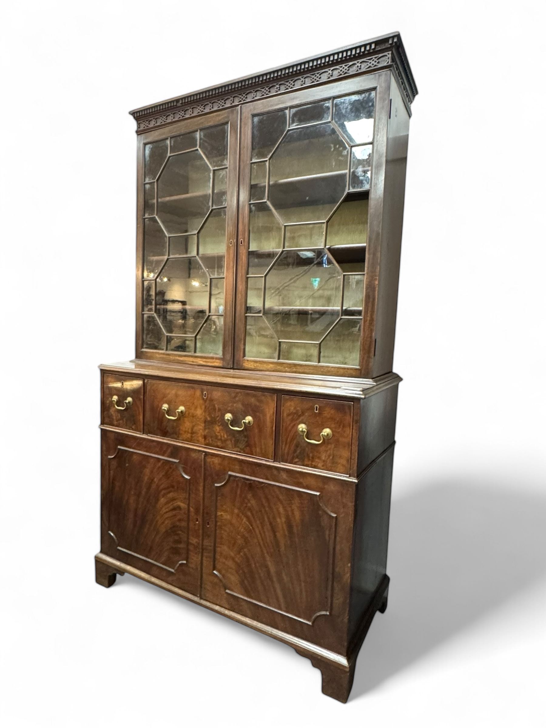 George III mahogany bookcase secretaire, dentil cornice over blind fret work frieze, enclosed by two astragal glazed doors, central secretaire drawer with fall front enclosing leather writing surface and small drawers, two flanking short drawers over double cupboard, on bracket feet