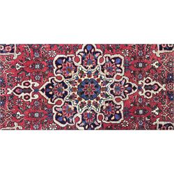Persian Hamadan crimson ground rug, central floral pole medallion with matching spandrels, the guarded indigo border with interlaced palmettes