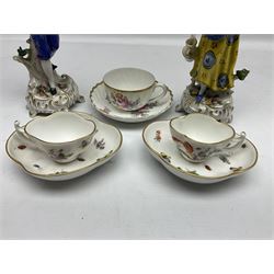Pair of Continental porcelain figures, modelled as a male and female figure with flowers, upon floral encrusted and C scroll bases, together with a pair of Continental cabinet cups and saucers, of quatrefoil form hand painted with flowers and butterflies, with printed marks beneath, and a German part fluted cup and saucer with similar decoration, in one box 
