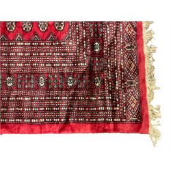 Persian Bokhara crimson ground carpet, the field decorated with repeating Gul motifs and lozenges, the multi-band geometric border with stylised plant motifs, two additional bands at the ends with geometric lozenges