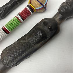 African carved hardwood twisted walking stick with carved figure to the top, together with decorative wooden training sword and two others