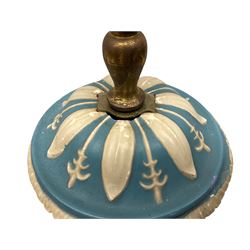 Ceramic urn shaped table lamp on a square pedestal base, decorated with relief studies of cherubs and foliage, on a blue ground, together with a cream pleated lampshade H60cm. 