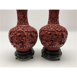 Pair of Chinese cinnabar lacquer vases, each of bulbous baluster form, carved with peonies and foo dogs amongst scrolls, with blue enamel interior and upon wooden bases, H20cm