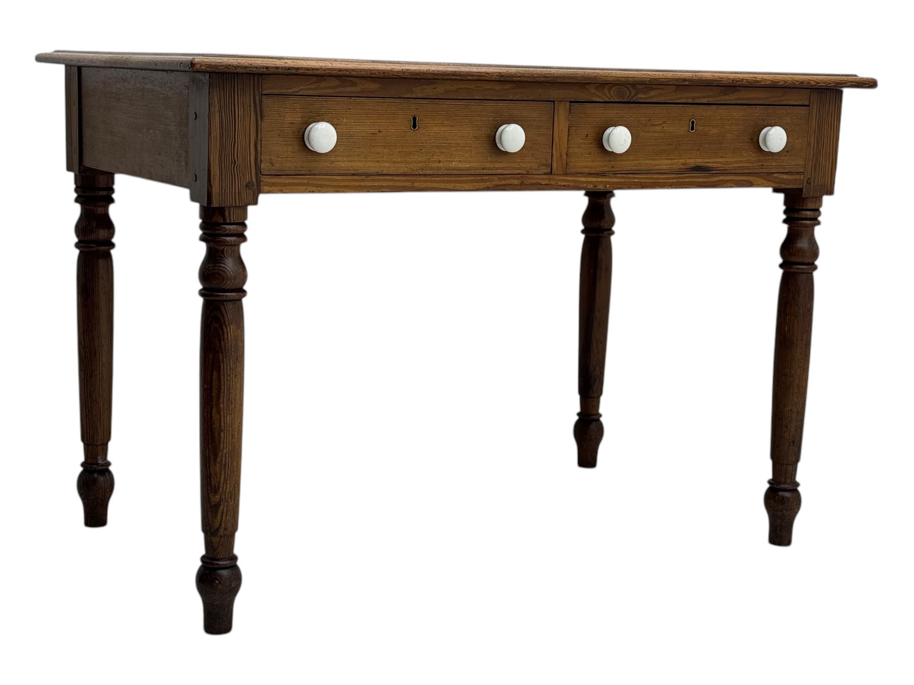 Victorian pine writing table, rectangular top with moulded edge and inset leather writing surface, the frieze fitted with two short drawers, raised by turned supports 