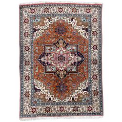 Large Persian carpet, the geometric and stylised floral medallion on rust ground field decorated with stylised plant motifs, guarded ivory border with repeating pattern