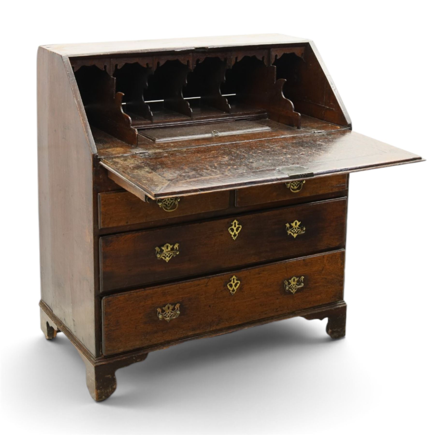 Georgian oak bureau, fall front with pierced brass escutcheon and handles, revealing a fitted interior, above two short over two long drawers, raised on bracket feet