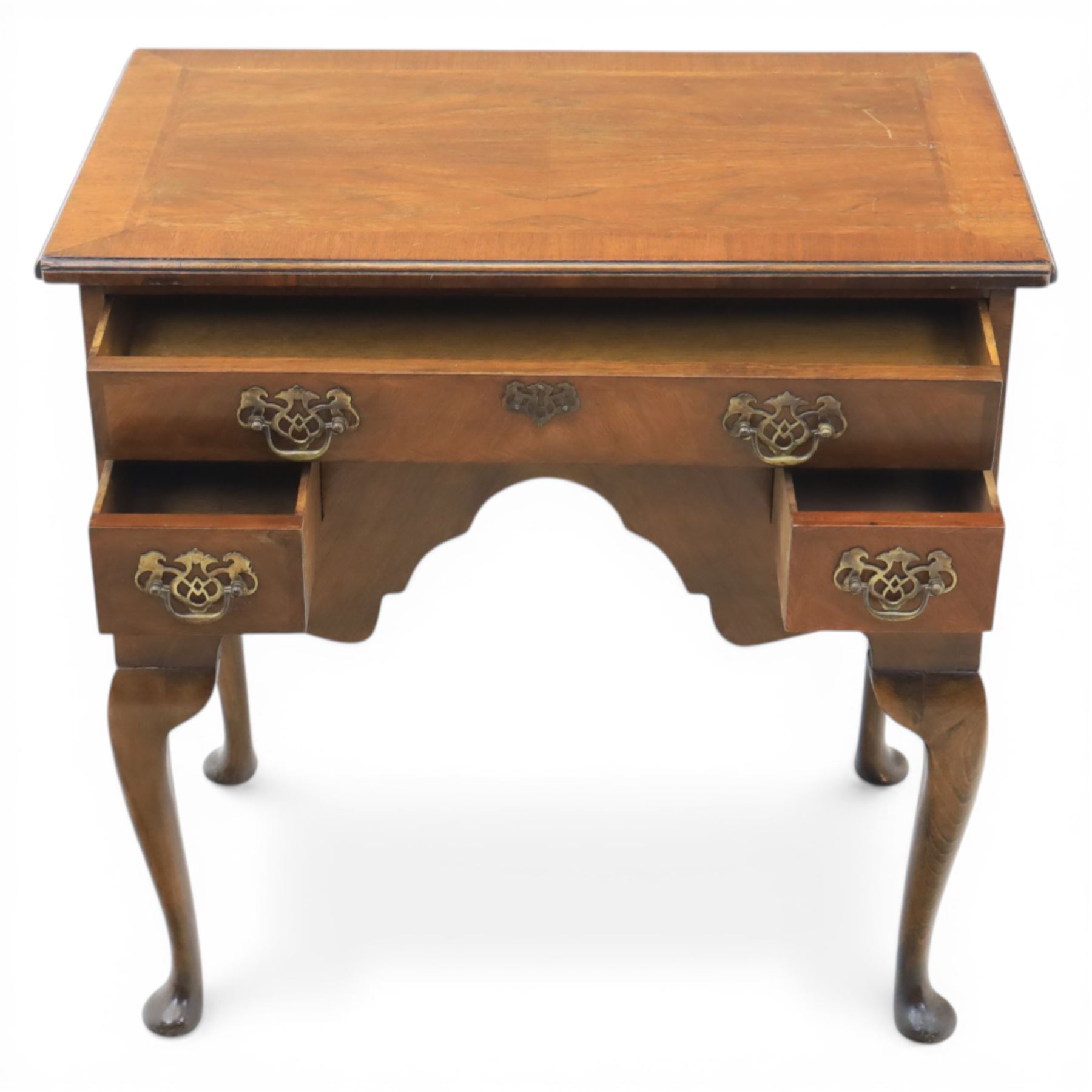 Early 20th century walnut lowboy in Queen Anne style, rectangular crossbanded top over single long drawer and two short drawers with shaped apron, fitted with brass drop handles and backplates, raised on cabriole supports terminating in pad feet