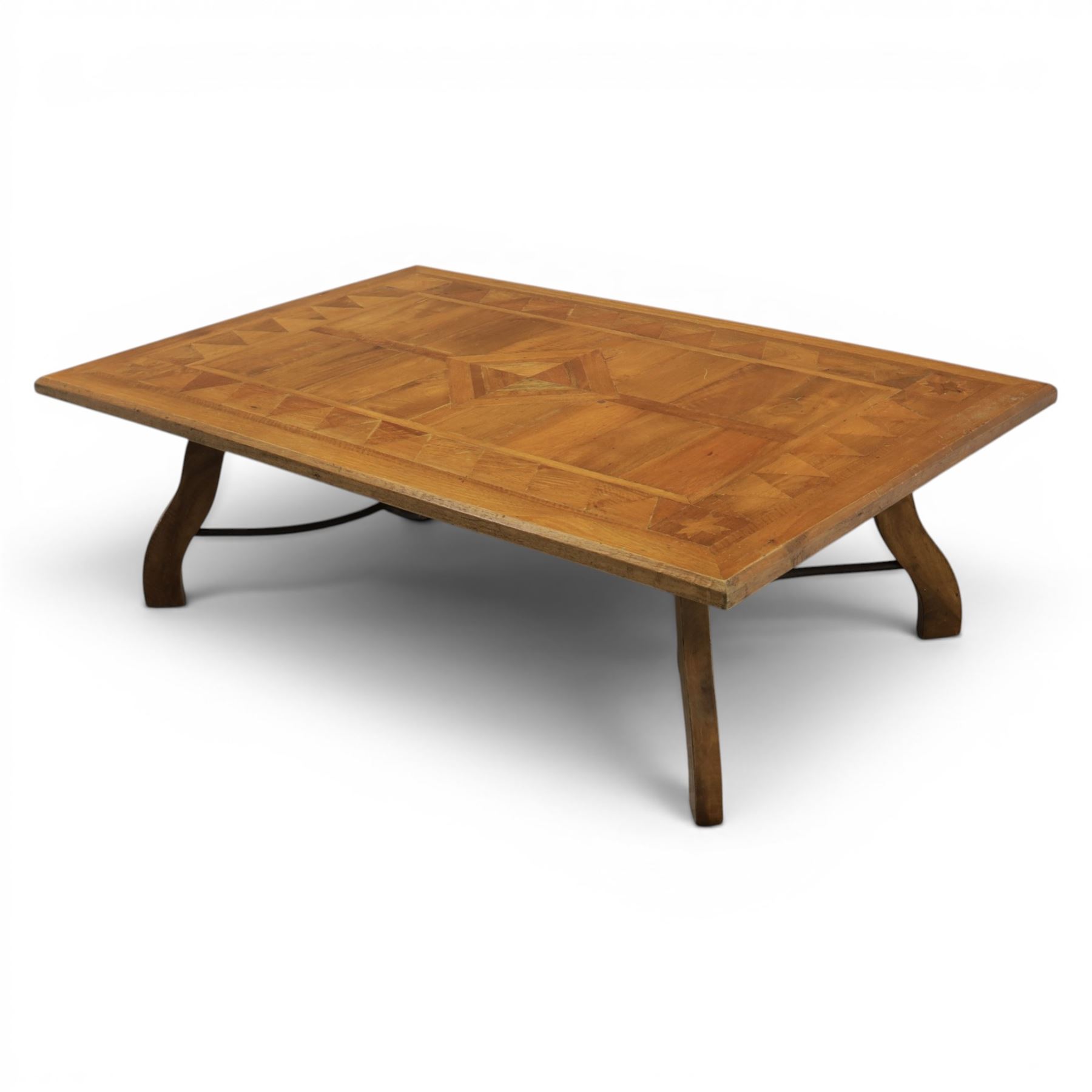 20th century Spanish design oak coffee table, rectangular parquetry top with geometric star and triangular inlaid decoration, moulded edge, on shaped trestle end supports united by black painted wrought iron scroll stretchers