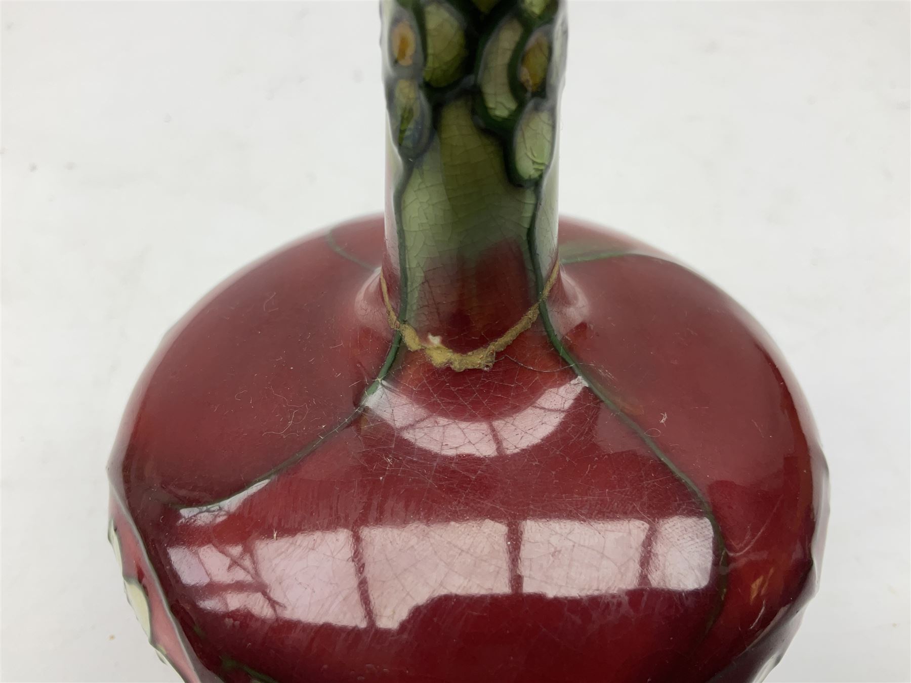 Three Minton Secessionist vases, with tube-lined stylised flower decoration, two upon a red ground and third upon a purple ground, all with printed mark to base 'Minton Ltd, No. 33', H13cm