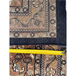 Large Persian indigo ground rug, the busy field decorated with trailing branches and flower heads, peach border decorated with palmettes -