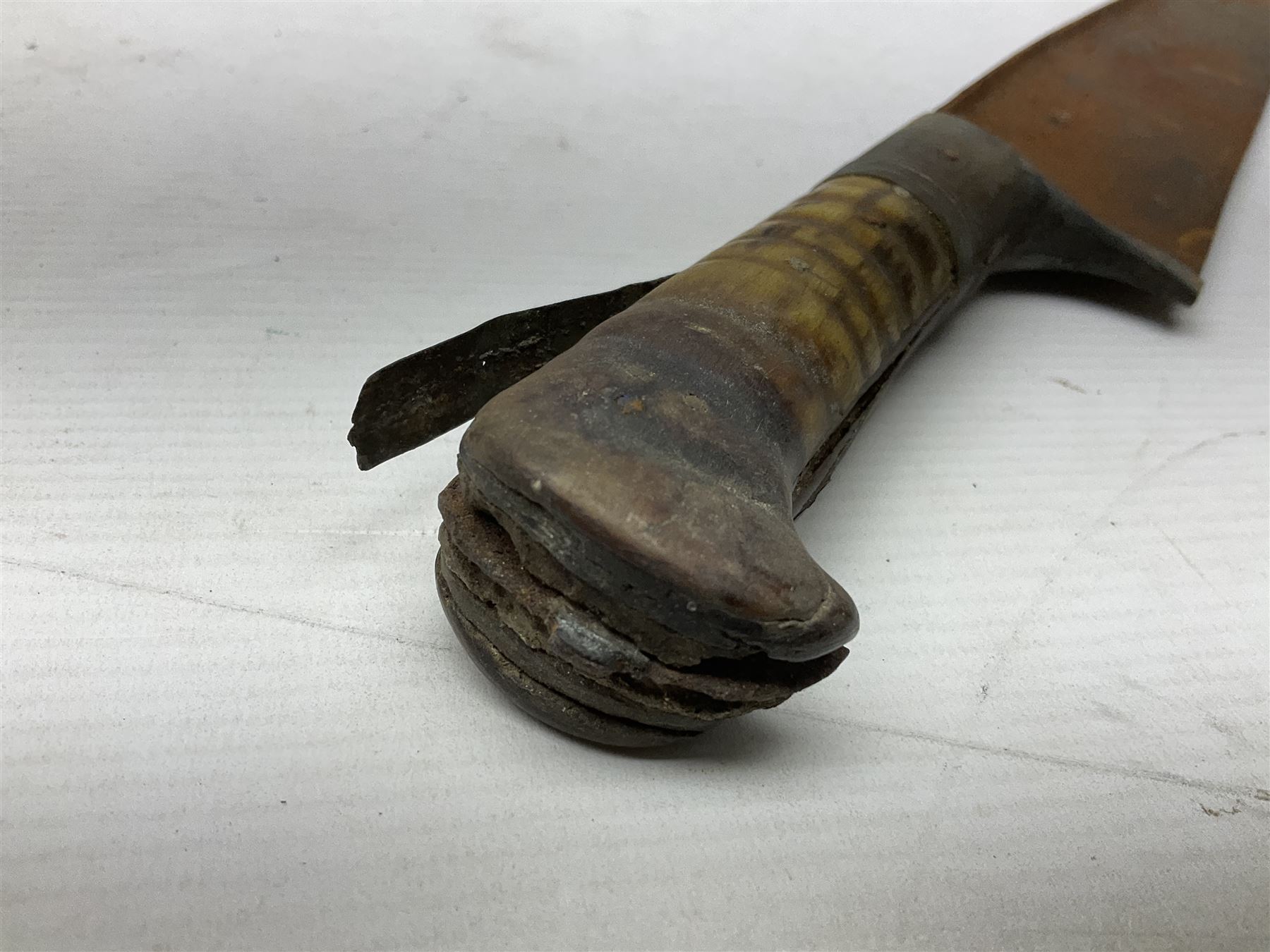 Mandingo sword, the 63cm plain curving steel blade marked with a horses head and the initials G.S.; leather covered grip with metal ribbed spherical pommel; in decorative leather leaf scabbard mounted with tassels and roundels L84cm overall; and a North African flyssa sword in poor condition with wooden scabbard (2)