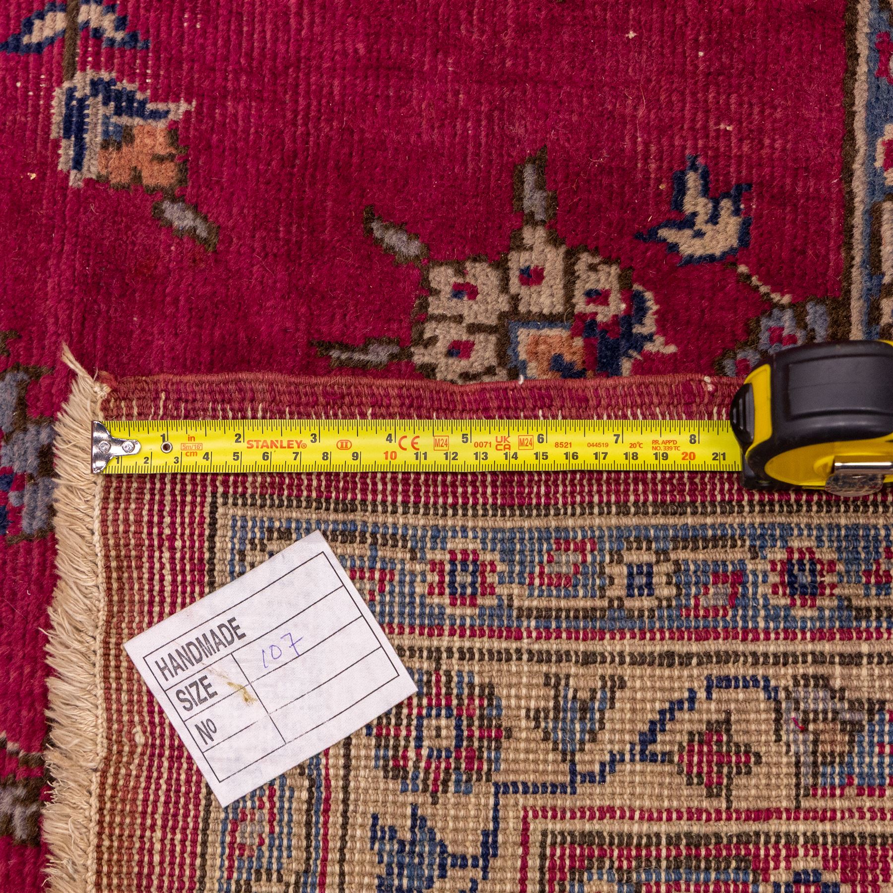 Large Persian-style mahal-type hand-knotted carpet, of rectangular form with a deep crimson field decorated with an all-over arrangement of stylized floral sprays and palmettes, with a central subtle medallion composition enclosed by a dark navy main border of scrolling floral motifs between narrow guard stripes with fringe ends 