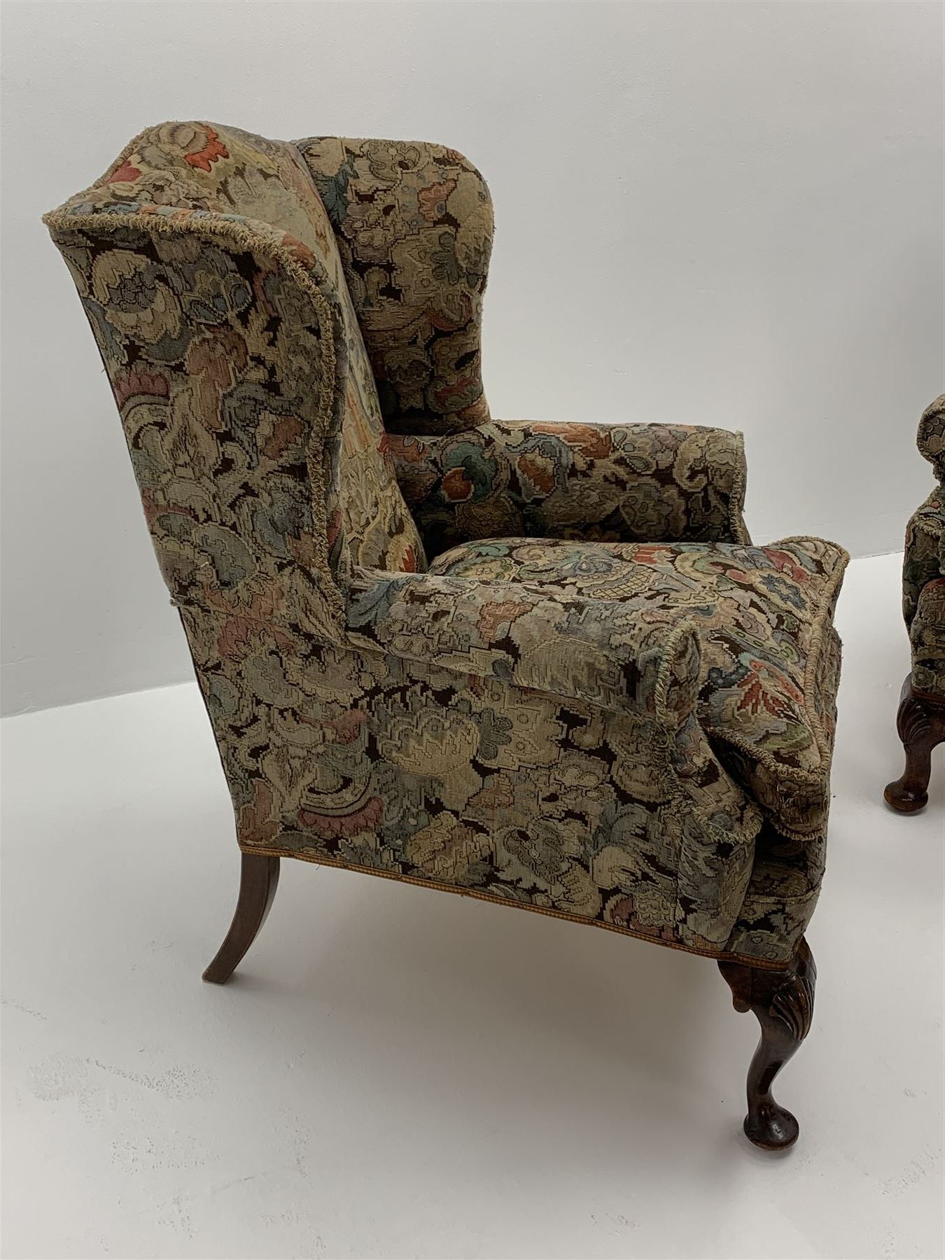 Matched pair early 20th century Queen Anne style wingback armchairs, walnut framed, sprung seats with seat cushions upholstered in needle work cover, shell carved cabriole front feet