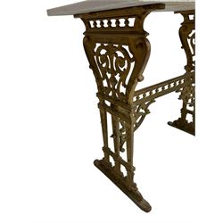 Pair of 19th century cast iron entrance tables, rectangular marble top over ornate gilt bases with scrolling foliate design and sledge feet, united by balustrade stretcher with scroll spandrels